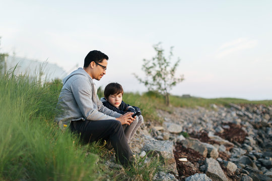 Father and son using a smart phone on grass