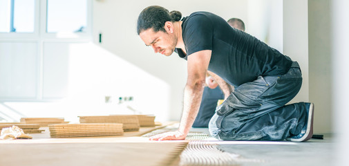 Handwerker verlegt eichen Parkett in fischgrätmuster 