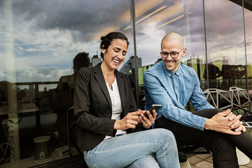 Friends laugh while looking at cell phone