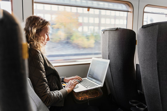 Young Woman Commuter On Train Using Laptop