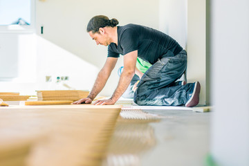 Carpenter on work putting wood parquet pieces. Home construction 