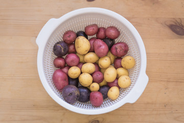 Tricolor mini potatoes in a basket on a wooden table washed and cleaned.