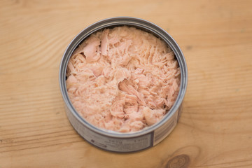 Open Can of Tuna in brine in a Silver Tin on a wooden table.