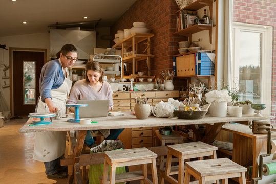 Women using laptop in pottery workshop