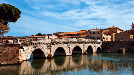 Obraz premium Tiberius bridge in Rimini on a background of blue sky with white clouds