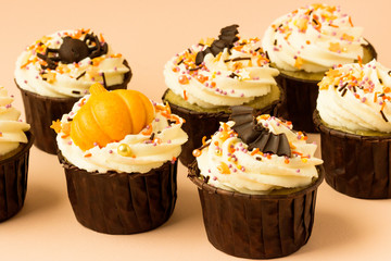Halloween cupcakes  with with bat, pumpkin, spiders on a pink background.