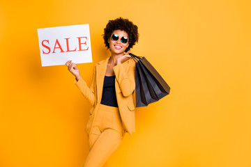 Portrait of positive cheerful afro american girl have sunglass free time on travel trip hold bags enjoy sales bargains want shop wear style fashionable outfit isolated over yellow color background