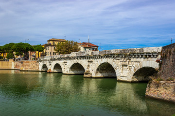 Naklejka premium Tiberius bridge in Rimini on a background of blue sky with white clouds