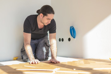 Handwerker verlegt eichen Parkett in fischgrätmuster 