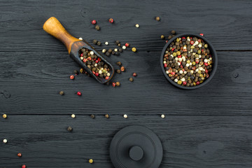 The  mixture of peppers of different colors in a black bowl on a black background.