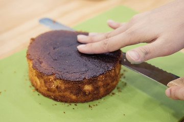 Making a layer cake. Cutting the top off of cakes with a serrated knife to level cake.