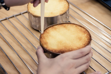 Woman removing baked cakes from the molds with a spatula.