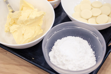 Sugar, butter, cream and white chocolate chips in a bowl for melting, preparing ingredients to make a cake.