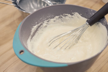 Cake mixture, batter in a plastic bowl with a whisk before baking.