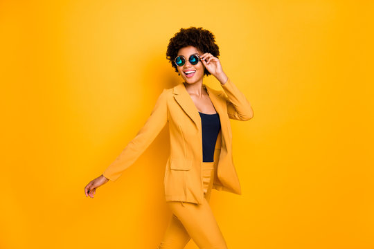 Profile side photo of charming positive cheerful dark skin lady touch her eyeglasses have free time go walk wear stylish clothes isolated over yellow bright color background