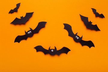 Composition of flying Halloween bats with funny eyes on orange