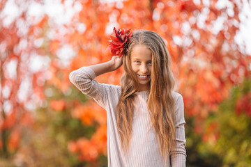 Portrait of adorable little girl with yellow leaves bouquet in fall