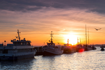 Fototapeta premium Fishing boats in harbor of Sassnitz at ruegen island. The sun sets in the background, Sassnitz, Ruegen Island