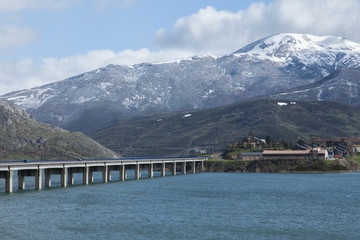 puente de Riaño con pantano lleno y nieve en las montañas