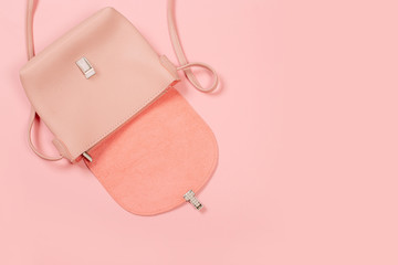Fashion concept : Flat lay of brown leather woman bag open out with cosmetics, accessories and smartphone on pink background