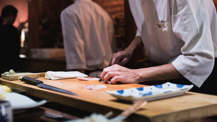 Chef preparing slicing fish for sushi, Omakase style Japanese traditional.