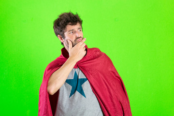 young crazy super hero thinking confused, disagree expression over green background
