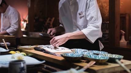 Chef preparing slicing oysters, Omakase style Japanese traditional. © Colin