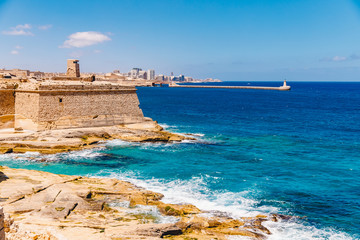 Fototapeta na wymiar Ancient stone military fort Malta island made of brick rocks on shore blue sea with view city Valetta