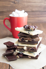 Pieces of white and dark chocolate with a cup of cocoa. Handmade chocolate with nuts and raisins. Menu and greeting card design.