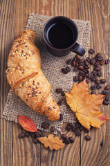 Coffee, croissant and autumn leaves