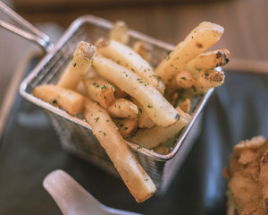Close-up of French fries in a fry bucket in a restaurant environment.
