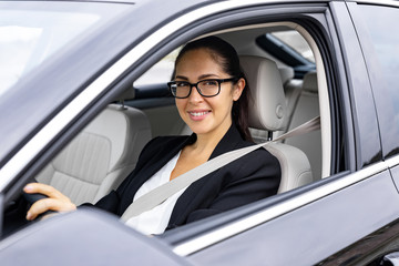 Beautiful young businesswoman is driving to work