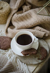 Cup of coffe with milk and chocolate cookies on warm wool blanket