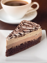 Slice of Tiramisu coffee cake on a white plate. Chose up of coffee chocolate layer cake.