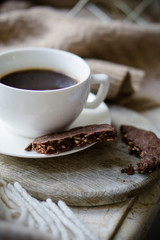 Cup of coffe with milk and chocolate cookies on warm wool blanket