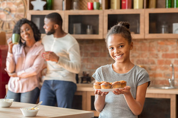 Smiling little girl demonstrating fresh puncakes at kitchen