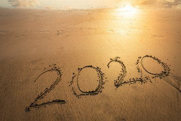 Happy New Year 2020 text on beautiful the sea beach with wave early morning sunrise over the horizon background.During Christmas and New Year.
