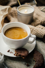 Cup of coffe with milk and chocolate cookies on warm wool blanket