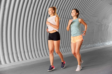 Fototapeta na wymiar fitness, sport and healthy lifestyle concept - young women or female friends running outdoors