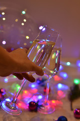 Glasses with champagne on a beautiful background of bright Christmas holiday lights. Christmas colorful toys for spruce. Photo with purple and yellow. 