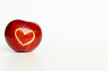 Beautiful bright juicy ripe red apple with a heart shaped cut-out, located on a white background....