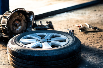Old wheel of the vehicle car for repair.Automobile mechanic in process of new tire replacement.Car brake repairing in garage.Car Service and technician concept.