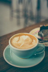 Cup of coffee latte in coffee shop.Beautiful foam,ceramic cups, place for text.Vintage tone.