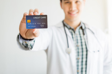 Asian Young man doctor therapeutic advising Abstract blur with focus show holding a credit card on...