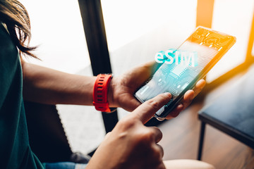 Close up of woman using a phone with eSIM technology. Mobile device with a chip on a circuit board art.eSIM(Embedded SIM) - electronic sim phone new mobile communication technology.