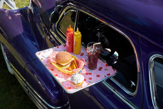 Typical American fast food on tray at vintage car, Chevrolet Fleetline