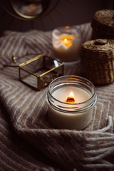 Burning hand-made candle with wooden wick in glass jar