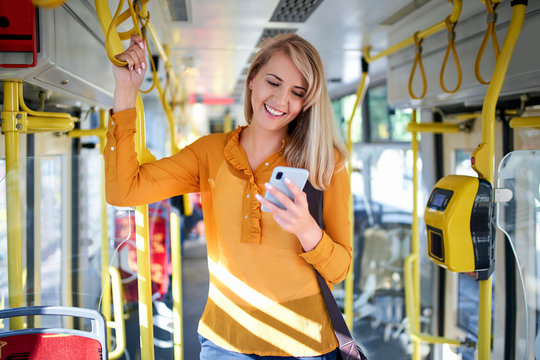 Smiling young woman using smartphone in a tram