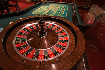 Casino, gambling and entertainment concept - roulette table and stack of poker chips