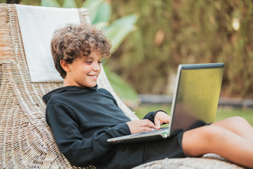 Relaxed boy using laptop on lounge in garden